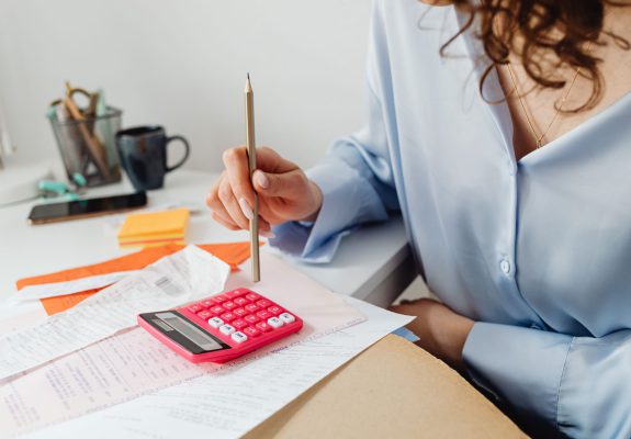 Mujer repasando recibos con una calculadora y un lápiz en su escritorio