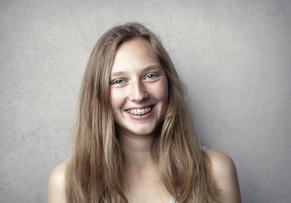 Chica joven sonriendo con brackets de ortodoncia