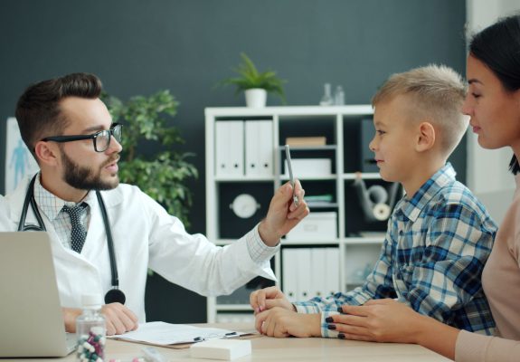 Médico explicando un tratamiento a un niño y a su madre en la consulta