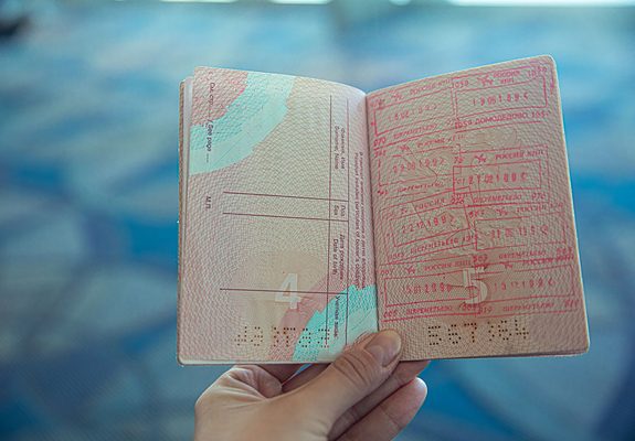 Pasaporte abierto con sellos de visado en la mano de un viajero